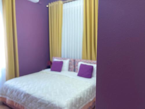 a bedroom with a bed with purple and yellow curtains at HOTEL VILA 15 - CENTER in Tirana