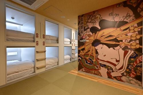 a room with bunk beds with a painting on the wall at Hotel Tomariya Ueno in Tokyo