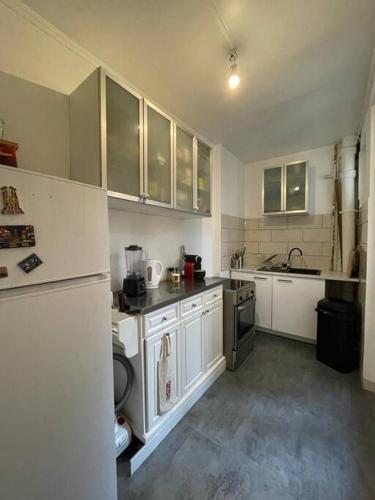 Elle comprend une petite cuisine avec des placards blancs et un réfrigérateur. dans l'établissement Joli 2 pièces à Pantin au porte de Paris, à Pantin