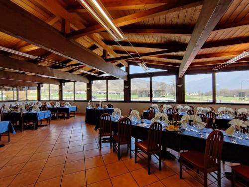 un comedor con mesas, sillas y ventanas en Albergo Baffo, en Chiuro