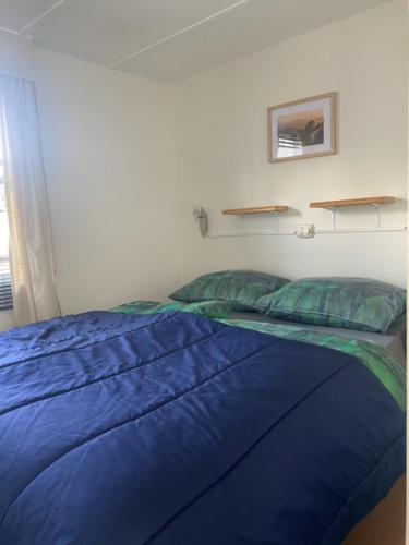 - un lit dans une chambre avec une couette et des oreillers bleus dans l'établissement Safarihuisje met airco!, à Oisterwijk