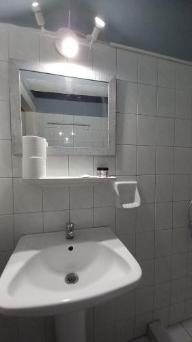 a white bathroom with a sink and a mirror at poros apartment in garden in Poros