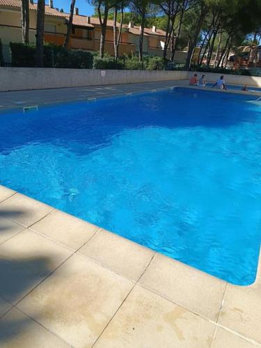une grande piscine bleue avec des personnes à l'arrière-plan dans l'établissement studio au cap d'agde dans les pinèdes, au Cap d'Agde