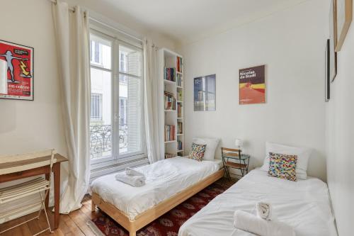 deux lits dans une chambre avec une fenêtre dans l'établissement Classic & Charming Parisian flat - Luxury 16th, à Paris