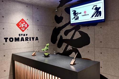 een tafel met een tv aan een muur met een bord bij Hotel Tomariya Ueno in Tokyo