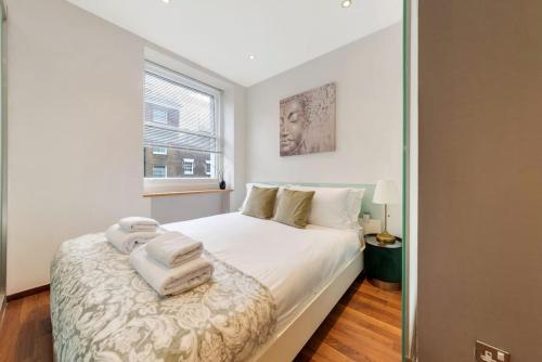 a bedroom with a bed with white sheets and a mirror at 1 Bedroom Edgeware Retreat in London