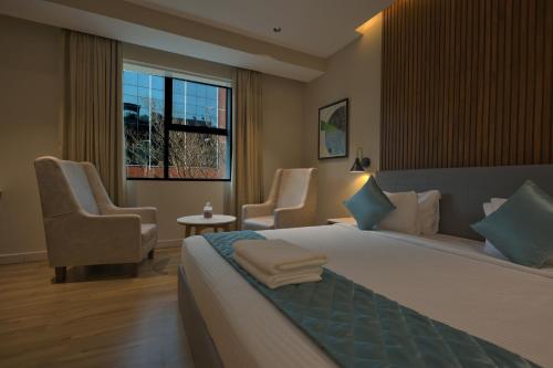 una camera d'albergo con un letto e due sedie di Hotel Aurum Keys - ORR Bagmane Tech Park a Bangalore