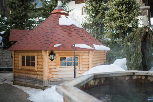a log cabin with a red roof in the snow at Hotel Sonklarhof in Ridanna