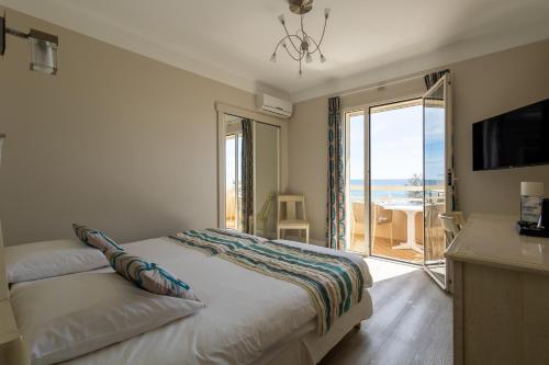 a bedroom with a bed with a view of the ocean at Hôtel Méditerranée in Le Lavandou