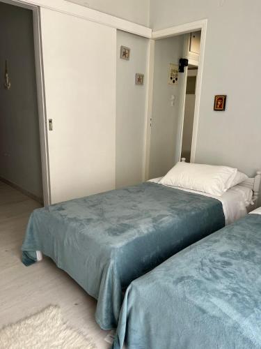 a bedroom with two beds with blue sheets at Sea View Apartments near Athens Airport in Artemida