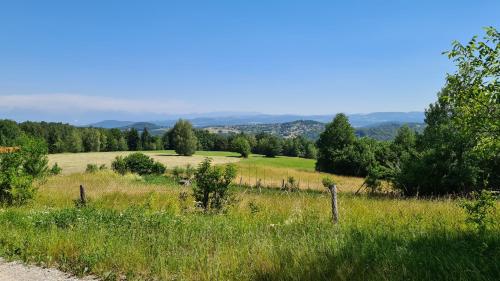 un campo de hierba con una valla y árboles en OAZA VISOKO, en Visoko