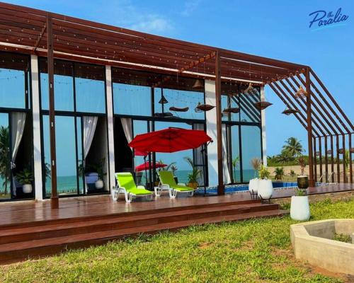 a house with a deck with chairs and an umbrella at The Paralia in Brunibuma