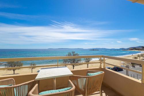 a balcony with a table and chairs and the beach at Hôtel Méditerranée in Le Lavandou