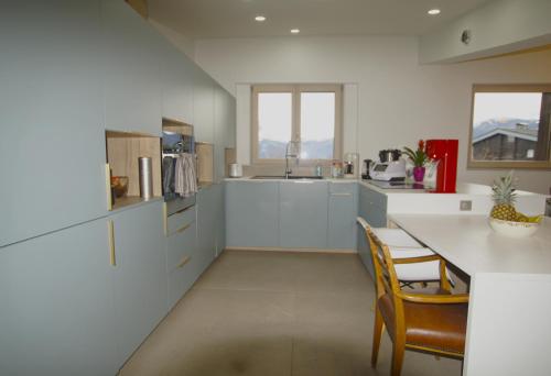 une cuisine avec des armoires blanches et une table et des chaises dans l'établissement le Cloumel Appt 8 pers 120 m terrasse 60m plein centre vue montagne, à Combloux