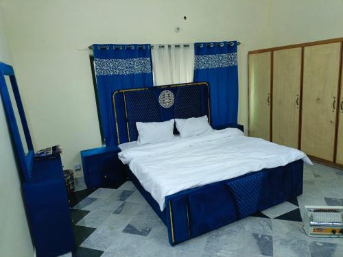 1 dormitorio con 1 cama azul con sábanas blancas en Prime Family Lodge, en Rawalpindi