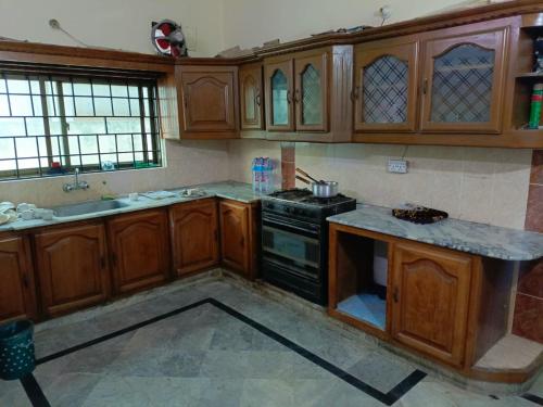 cocina con armarios de madera y horno con fogones en Prime Family Lodge, en Rawalpindi