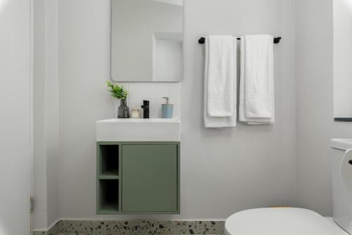 a white bathroom with a toilet and a sink at Neighbourgood 1st Crescent Camps Bay in Cape Town