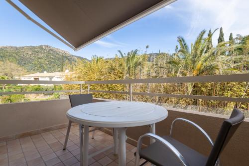a table and chairs on a balcony with a view at Hôtel Méditerranée in Le Lavandou