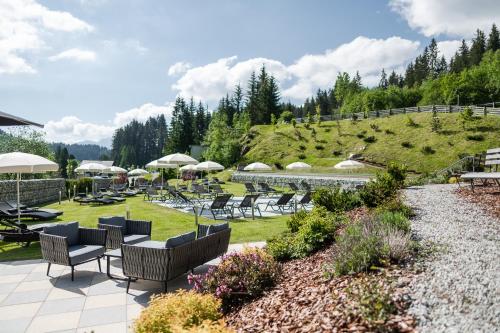 a patio with chairs and tables and a hill at Hotel Sonklarhof in Ridanna