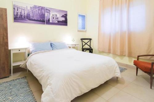 1 dormitorio con 1 cama blanca grande y 1 silla en Sunny Home by the Sea en Tel Aviv