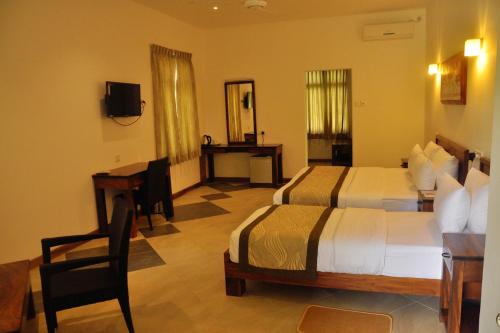 a hotel room with two beds and a desk at Spring Villas Kandy in Kandy