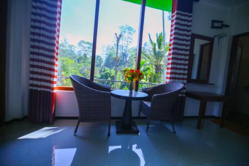 a table with chairs and a vase of flowers on it at Ella Nine Arch lodge in Ella