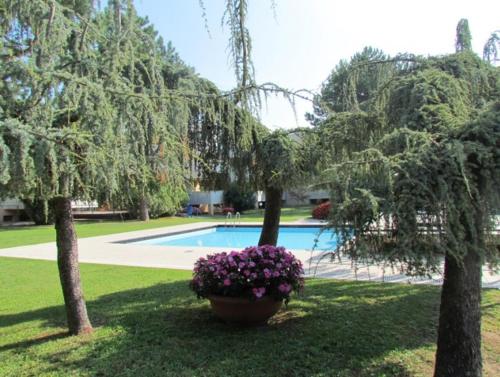 einen Garten mit einem Pool sowie Bäumen und Blumen in der Unterkunft Nice Apartment with Pool and Tennis court - Beach Place Included by Beahost in Bibione