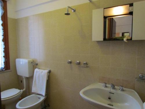 ein Badezimmer mit einem Waschbecken, einem WC und einem Spiegel in der Unterkunft Nice Apartment with Pool and Tennis court - Beach Place Included by Beahost in Bibione