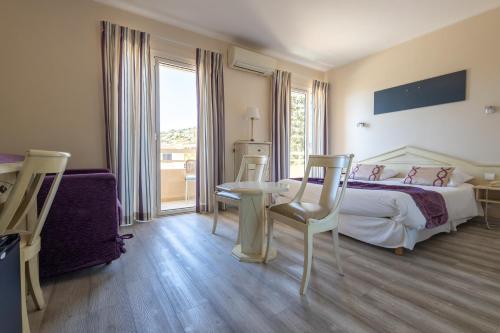 a bedroom with a bed and a table and chairs at Hôtel Méditerranée in Le Lavandou