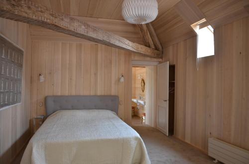 a bedroom with a bed in a room with wooden walls at Le Pavillon de l'Orangerie in Meursanges