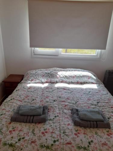 a bedroom with a bed with a flowered blanket and a window at LA CHABELA in Trevelín
