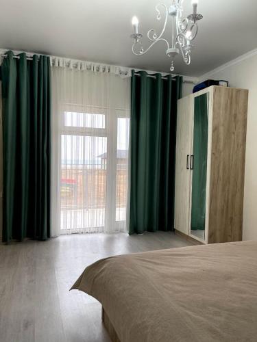 a bedroom with green curtains and a bed and a chandelier at Ak Line in Bosteri