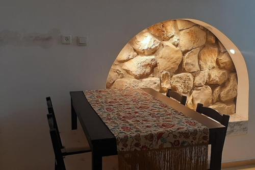 una mesa y sillas con una pared de piedra en Two stand-alone flats on the cliff with wild animals, Galilee Sea & Mountains View, en Safed