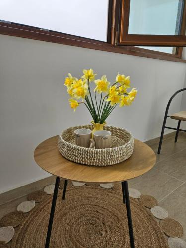 a table with a vase of yellow flowers on it at Tei Residence in Piatra Neamţ