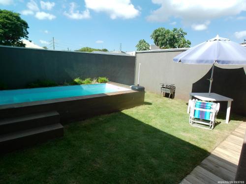 a small backyard with a swimming pool and an umbrella at Casa aconchegante com piscina e bem localizada in Foz do Iguaçu
