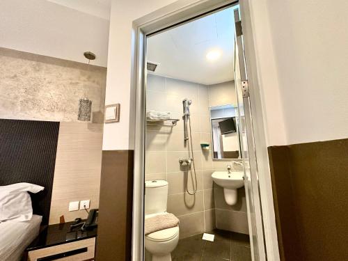 a bathroom with a shower and a toilet and a sink at The Snooze Hotel at Bugis in Singapore