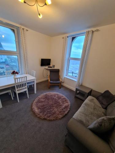 a living room with a couch and a table and two windows at Farina No6, Sea view apartment sleeping 4 guests in Bridlington