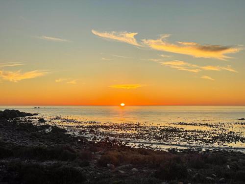 a sunset over a beach with the sun setting at Magical Mongoose in Jacobs Bay