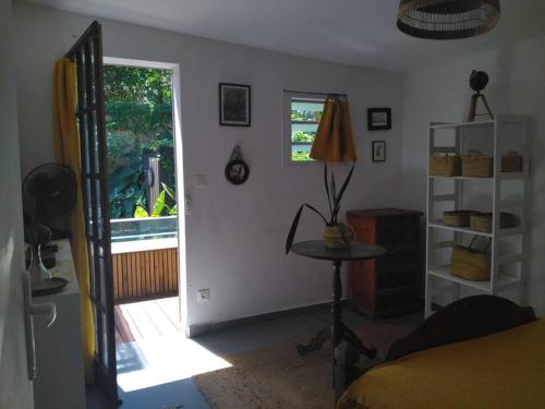 una camera con un letto, un tavolo e una finestra di La petite case jaune , jaccuzi pierre à 3 min à pied du bassin Manapany, vue mer a Saint-Joseph