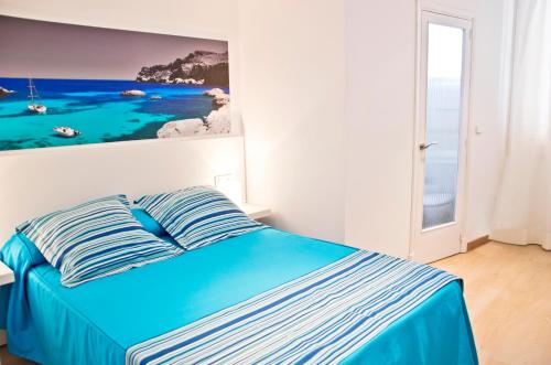 a bedroom with a blue bed with a painting on the wall at Hotel Capri in Port de Pollensa