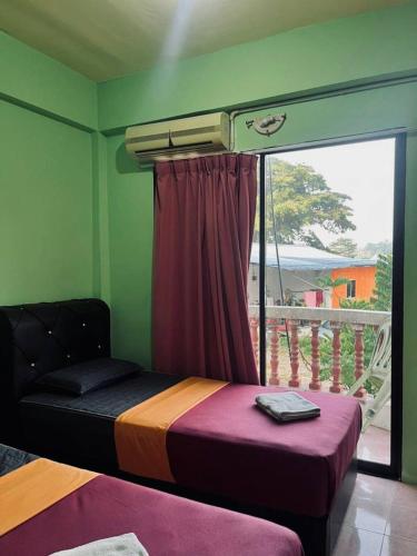 a bedroom with a bed and a window with a balcony at Teresek View Motel in Kuala Tahan