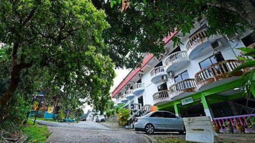 a car parked in front of a building with balconies at Teresek View Motel in Kuala Tahan