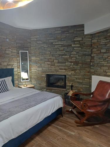 a bedroom with a bed and a chair and a fireplace at Bella Gaia in Eleftheroúpolis