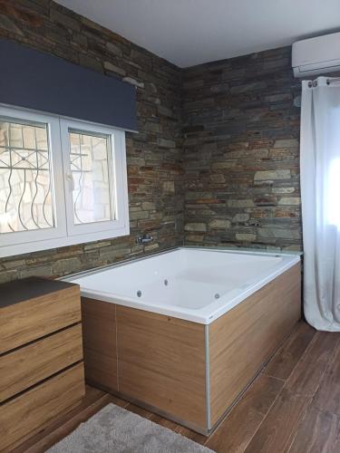 a bath tub in a room with a brick wall at Bella Gaia in Eleftheroúpolis