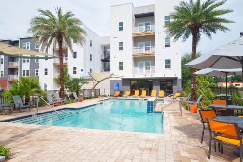 basen w hotelu ze stołami, krzesłami i palmami w obiekcie Deluxe One Bedroom Apartment w mieście Gainesville