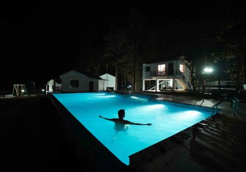 a person laying in a swimming pool at night at Misty Dam Wayanad Premium Resort With Banasura Dam View in Padinjarathara