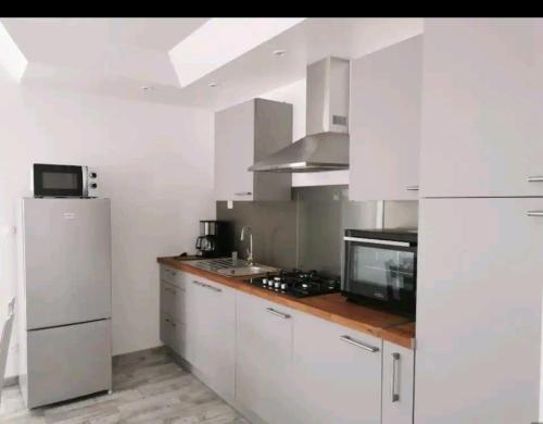 eine Küche mit weißen Schränken und einem Kühlschrank in der Unterkunft La petite maison in Monthermé