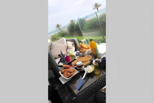 a table with food on top of a balcony at Appartement de luxe en bord de mer avec piscine in Mansouria