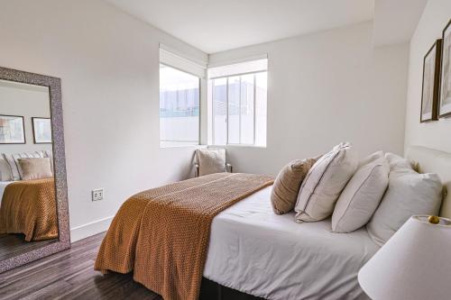 een slaapkamer met een bed met kussens en een spiegel bij Modern 2BD & 2BTH Santa Monica 5 min to the Pier in Los Angeles