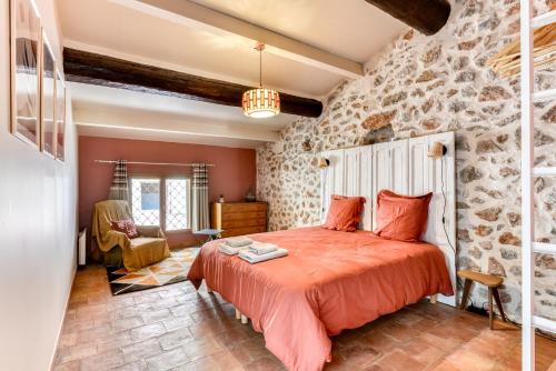 um quarto com uma cama e uma parede de pedra em Le Grappillon em Fitou
